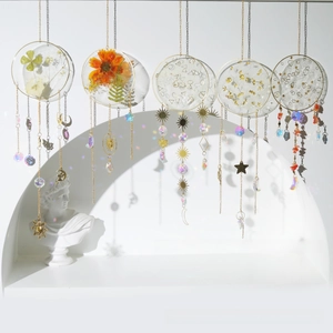 Detail of five hanging crystal suncatchers with dried flowers and gold foil elements