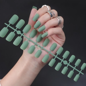 Macro shot of matte green long square press-on nails arranged on an injection strip
