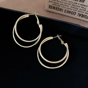 Detail of gold layered hoop earrings with textured mesh and polished finish design