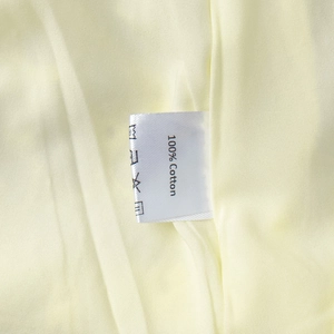 Detailed view of the 100% cotton wash care label on a soft yellow cotton dress