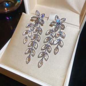 Close-up of silver floral leaf earrings with sparkling crystals in a beige jewelry box