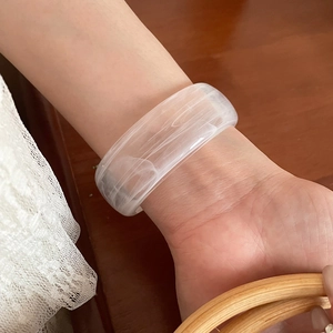 Macro shot of translucent white resin bangle with marble texture on wrist