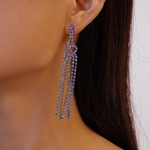 Close-up of geometric purple crystal tassel earrings worn by a model in a side view