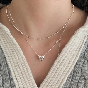 Close-up of a double-layered 925 sterling silver heart necklace worn by a model