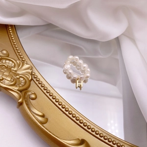 Macro view of freshwater pearl ring featuring a golden letter H charm on mirror