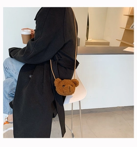 Detailed view of a cute brown plush bear-shaped crossbody bag worn with a black coat