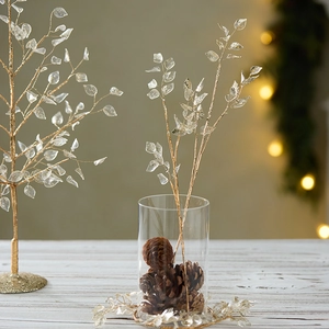 Artificial golden Christmas branch with frosted acrylic leaves in a glass vase decor