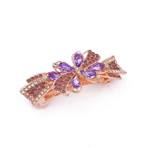 Detail view of purple rhinestones and white crystals on golden alloy bow hair clip