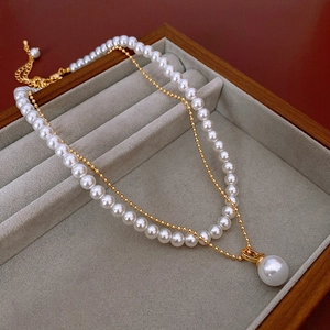 Détail d'un élégant collier double rang en or avec perles blanches et pendentif