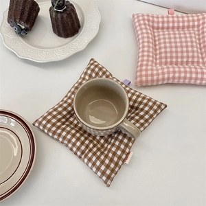 Détail d'un dessous de verre rembourré à carreaux marron avec une tasse de café