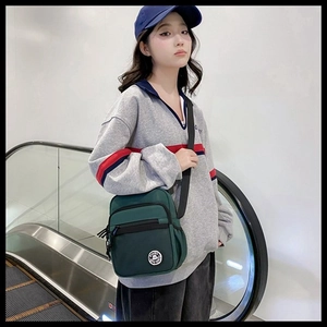 Detail of dark green canvas crossbody bag with adjustable strap and multiple zippers