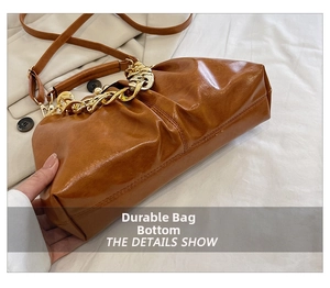 Detail shot of caramel brown pleated bag showing durable bottom stitching and leather texture