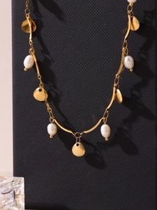 Detail of golden stainless steel necklace with seashell charms and white pearls