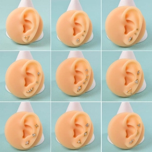 Various golden stainless steel ear studs with zircon crystals on silicone ear models