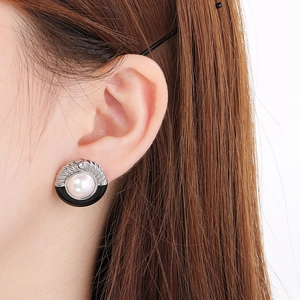 Detail of French vintage pearl earrings with black drip oil and silver wing accents on model