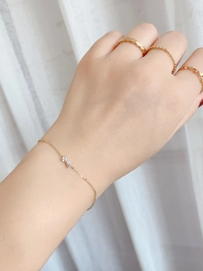 Detail of S925 silver bow bracelet with heart zircon worn with gold rings on hand