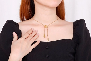 Détail d'un collier en Y doré ajustable avec curseur cœur et breloques garçon et fille