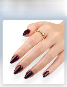 Gros plan d'ongles amande dégradé rouge foncé brillant avec bague dorée ornée