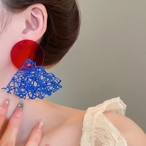Gros plan sur des boucles d'oreilles en maille rouge et bleu au design rétro chic