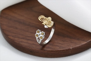 Detailed macro view of a silver honeycomb ring featuring a golden bee and yellow gemstones