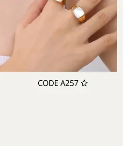 Close-up of a gold signet ring with square white inlay worn on a model's finger