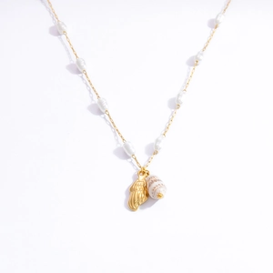 Close-up of golden pearl necklace with metallic shell and natural conch pendants