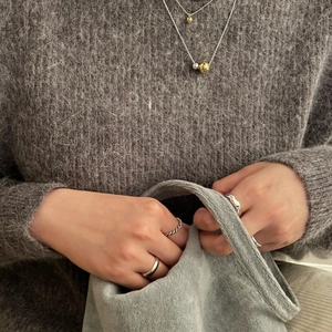 Close-up of minimalist layered sterling silver ball necklace and rings on a model