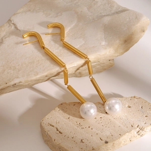 Elegant gold stainless steel tassel earrings with round pearls on a stone background