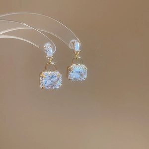 Detailed close-up of golden square padlock earrings with sparkling cubic zirconia inlay