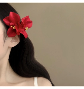 Detalle de un pasador de flores de orquídea roja usado por una modelo para un estilo vacacional.