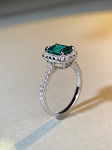 Macro detail of emerald-cut green stone ring with small zircon diamonds in silver