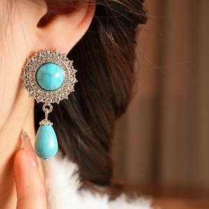Close-up of vintage silver earrings with rhinestones and green turquoise drop pendants