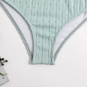 Detail of mint green bikini fabric featuring vertical stripes and laser cut eyelets