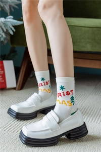 Gros plan de mocassins en cuir blanc à semelles épaisses et chaussettes à motif de Noël