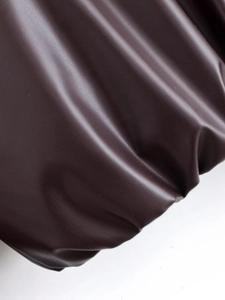 Détail de la texture macro du similicuir marron foncé avec plis naturels sur la veste