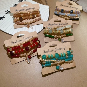 Detailed set of multi-layer crystal bead bracelets with gold alloy charms on paper fan