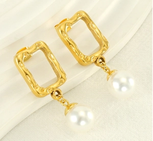Detail of gold rectangular earrings with textured surface and hanging white pearl