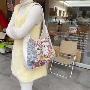 Detail view of cartoon bear canvas tote bag featuring dog and tree illustration in use