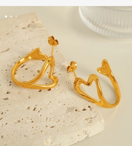 Detailed close-up of golden hollow heart earrings on beige stone for a modern look