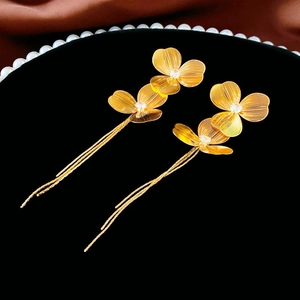 Macro view of gold vintage flower tassel earrings with clear zircon center and brushed texture