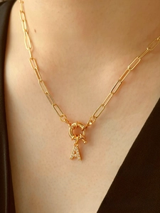 Detail of paperclip chain necklace with micro-paved zircon letter A pendant on a model