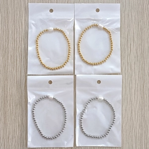 Detail of 4mm gold and silver beaded bracelets with freshwater pearls in individual packaging