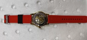 Vue détaillée du fond transparent montrant le mouvement mécanique squelette et bracelet rouge