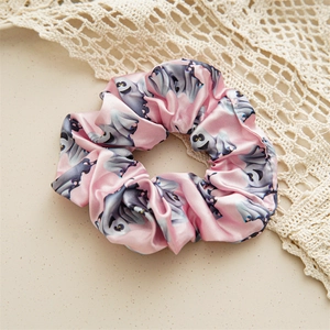Pink satin Halloween scrunchie with grey ghost patterns on a textured background