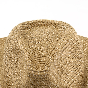 Detailed macro view of brown straw hat crown featuring white stitching and gold sequins