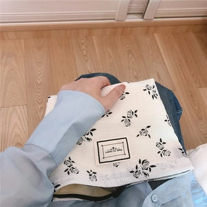 Detail of floral seersucker handbag featuring 'TIME TO PARTY' label and black zipper