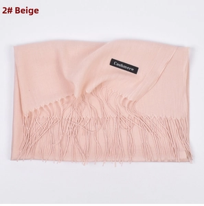 Detailed close-up of beige cashmere scarf with elegant fringe trim and woven product label