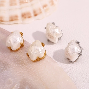 Macro detail of Baroque style faux pearl earrings with gold and silver claw settings