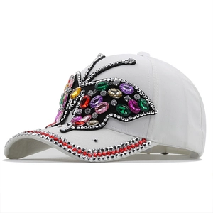 Detail of white baseball cap with large colorful rhinestone butterfly and studded brim