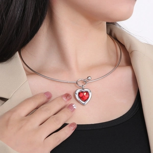 Close-up of a red heart-shaped gemstone pendant on a silver steel choker necklace